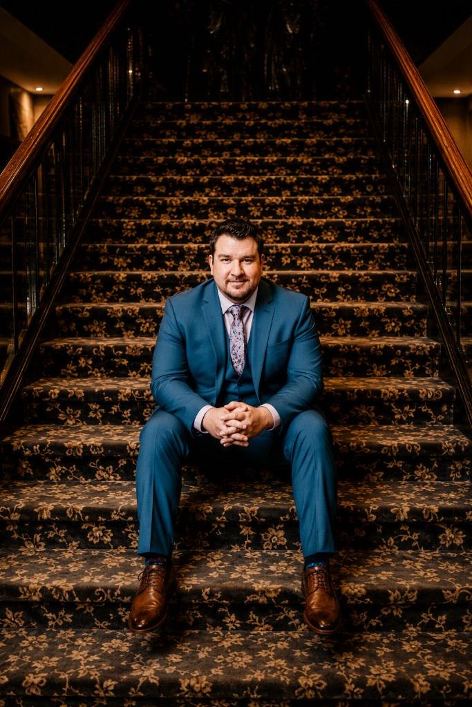 OSN Founder seated on a grand staircase in a blue suit